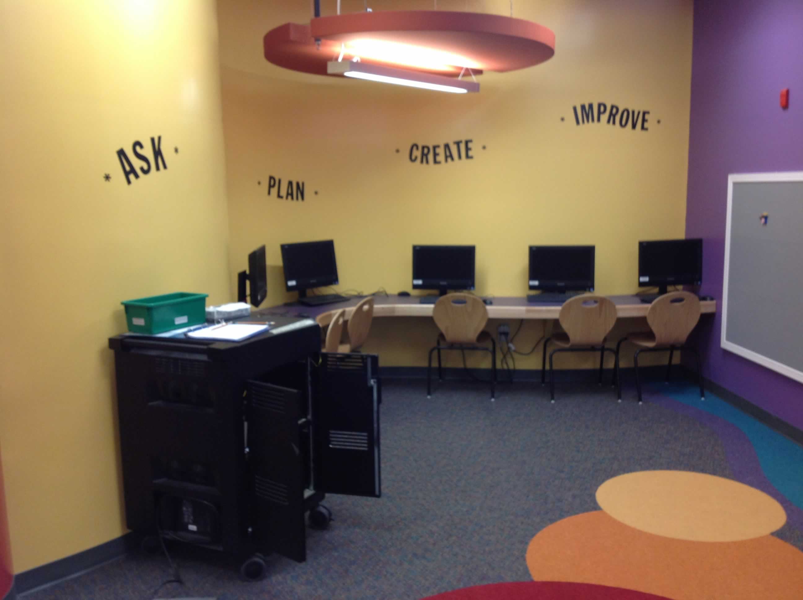 this is and image of a learning commons area with a laptop cart and some desktop computers